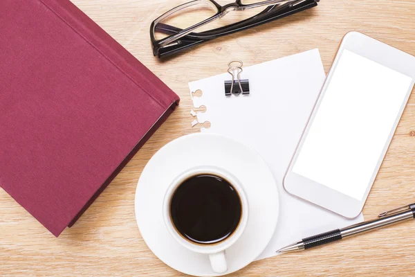 Vista superior de escritorio de oficina de madera con teléfono inteligente blanco en blanco, taza de café, libro rojo cerrado, gafas, hoja de papel, clavija y pluma. Prepárate. —  Fotos de Stock