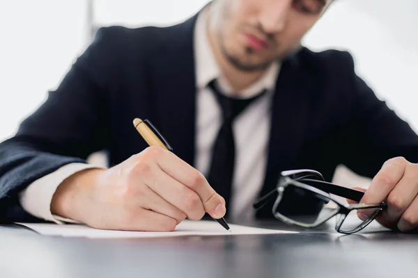 Escribiendo hombre sosteniendo gafas — Foto de Stock