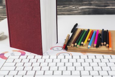 Workplace with keyboard, book and supplies