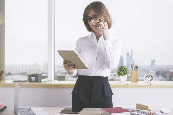 Kvinna på telefon läsning anteckningar — Stockfoto