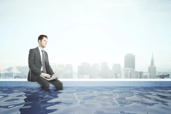 Businessman with laptop in rooftop pool — Stock Photo, Image