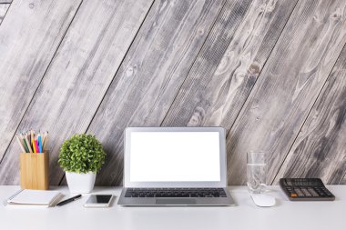 Boş beyaz dizüstü bilgisayar, akıllı telefon, hesap makinesi, bitki, kırtasiye öğeleri, su bardağı ve diğer öğeleri ile yaratıcı tasarımcı masaüstü ön görünümü. Alay etmek