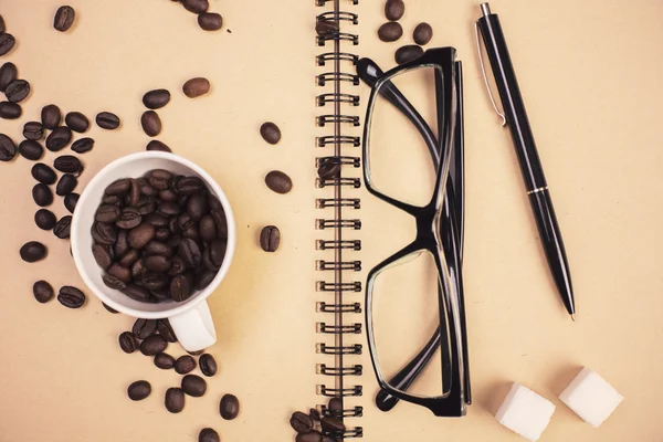 Grãos de café e copos no bloco de notas — Fotografia de Stock