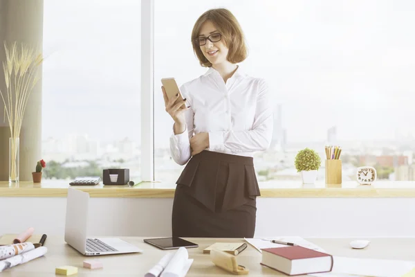 Femme au bureau utilisant un smartphone — Photo