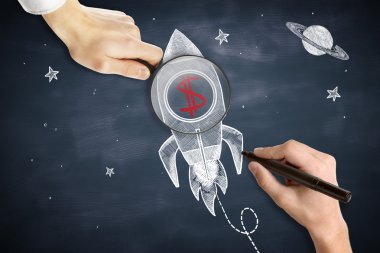 Erkek elleri çizim ve kırmızı dolar işareti ile uzay gemisi şiş üzerinde büyüteç tutarak. Tebeşir tahtası arka planı. Başlangıç konsepti