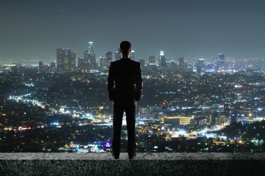 Işıklı gece şehrine bakan çatıdaki işadamının arka görünümü. Araştırma konsepti