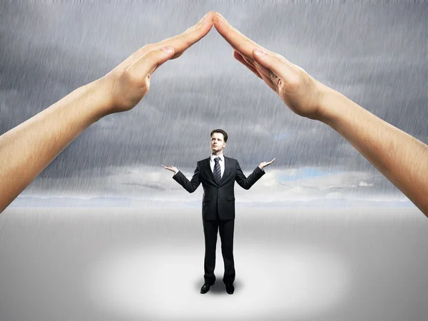 Empresário de pé sob as mãos juntos como um telhado da casa, protegendo-o da chuva. Conceito de segurança — Fotografia de Stock