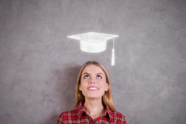 Beton duvardaki harç tahtası çizimine bakan çekici genç kadının portresi. Mezuniyet konsepti