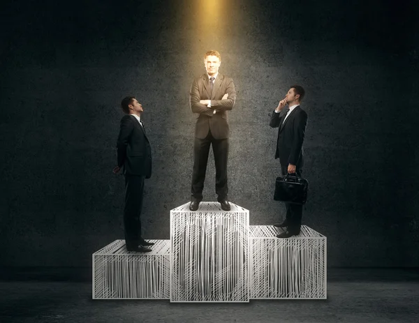 Tres hombres de negocios en el podio del ganador. Fondo de pared de hormigón . — Foto de Stock