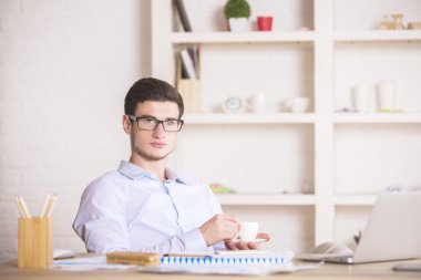 Genç adam kahve içiyor.