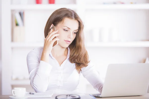 Mujer en el teléfono usando el ordenador portátil — Foto de Stock