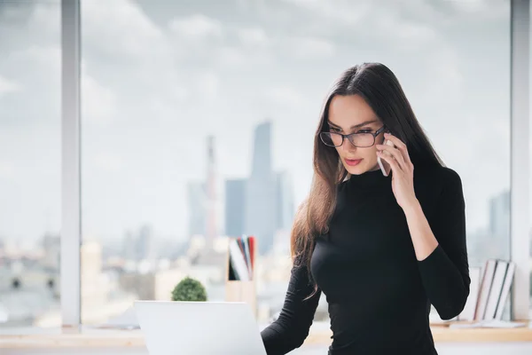 Mujer en el teléfono usando el ordenador portátil — Foto de Stock