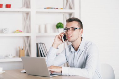 Young man on phone using laptop