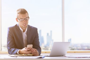 Gülümseyen işadamı akıllı telefon kullanıyor.