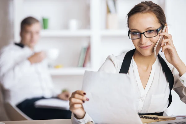 Jonge vrouw op telefoon doen papierwerk — Stockfoto