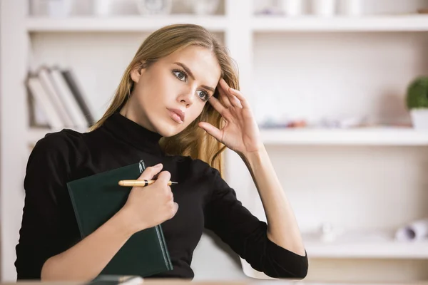 Girl with notepad thinking at workplace