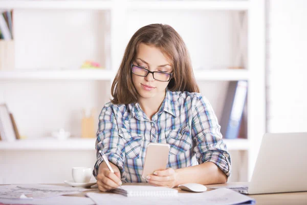 Woman using cell and doing paperwork — ストック写真