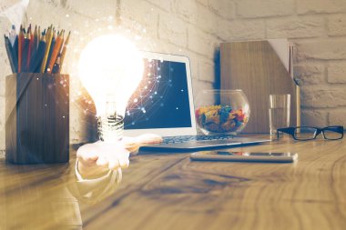 Bilgisayar ofisinde ampul simgesi hologramıyla birlikte. Çifte maruziyet. Fikir kavramı.