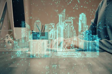 Arka planda bilgisayar üzerinde çalışan bir iş adamı ile yüksek teknoloji şehir çizimi. Akıllılık konsepti. Çift pozlama.