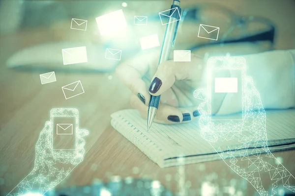 E-mail envelop theme hologram over hands taking notes background. Concept of electronic mail. Double exposure