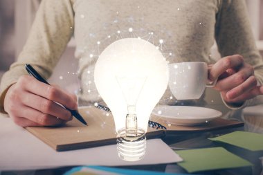 El üstünde tutulan ampul hologramı notlar alıyor. Fikir kavramı. Çift pozlama