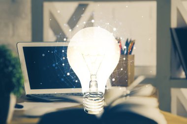 Bilgisayar ofisinde ampul simgesi hologramıyla birlikte. Çifte maruziyet. Fikir kavramı.
