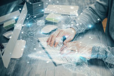 Arkaplanda bilgisayar üzerinde çalışan bir iş adamıyla zarf hologramı çizimi. Elektronik posta konsepti. Çift pozlama.