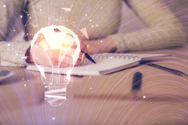 El üstünde tutulan ampul hologramı notlar alıyor. Fikir kavramı. Çift pozlama