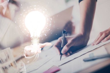 El üstünde tutulan ampul hologramı notlar alıyor. Fikir kavramı. Çift pozlama