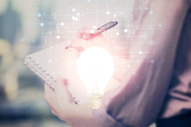 El üstünde tutulan ampul hologramı notlar alıyor. Fikir kavramı. Çift pozlama