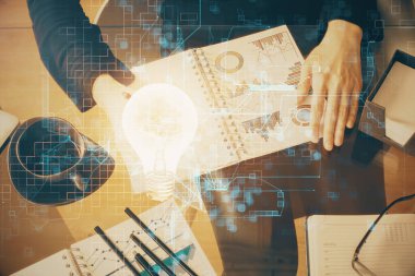 El üstünde tutulan ampul hologramı notlar alıyor. Fikir kavramı. Çift pozlama