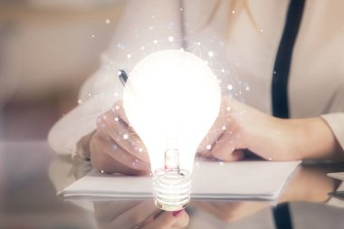 El üstünde tutulan ampul hologramı notlar alıyor. Fikir kavramı. Çift pozlama