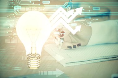 El üstünde tutulan ampul hologramı notlar alıyor. Fikir kavramı. Çift pozlama