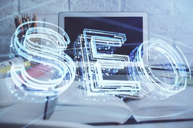 Bilgisayar ve seo çizim hologramı olan bir masanın çifte görüntüsü. Arama optimizasyon kavramı.