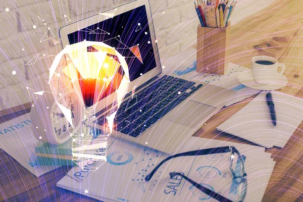 電球アイコンのホログラムを持つオフィスのデスクトップ上のコンピュータ。露出を2倍。アイデアの概念. — ストック写真