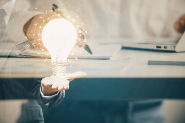 El üstünde tutulan ampul hologramı notlar alıyor. Fikir kavramı. Çift pozlama