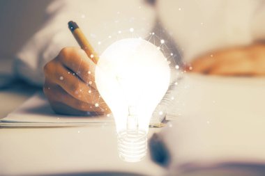 El üstünde tutulan ampul hologramı notlar alıyor. Fikir kavramı. Çift pozlama