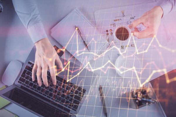 Multi exposure of mans hands typing over computer keyboard and forex graph hologram drawing. Top view. Financial markets concept.