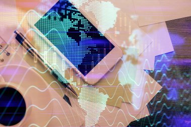 Forx grafik hologramının telefonlu masaüstü üzerinde çoklu pozlandırılması. Üst Manzara. Mobil ticaret platformu kavramı.