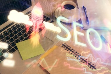 SEO yazılarını ve masaüstünü kahve ve masa arkasında eşyalar eşliğinde iki kez görüntüle. Arama optimizasyonu kavramı.