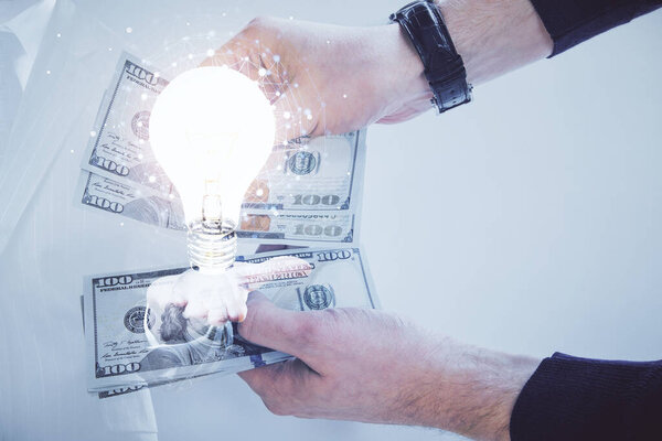 Multi exposure of bulb drawing hologram and USA dollars bills and man hands. Business Idea concept.