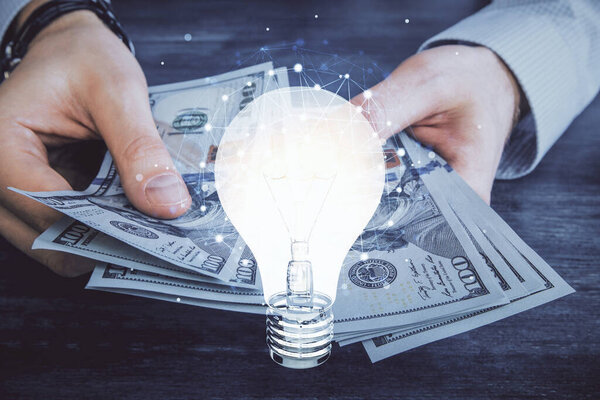 Multi exposure of bulb drawing hologram and USA dollars bills and man hands. Business Idea concept.