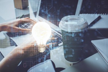 Bilgisayarda yazı yazan ve ampul çizen bir kadının ellerine iki kez maruz kalmış. Fikir kavramı.