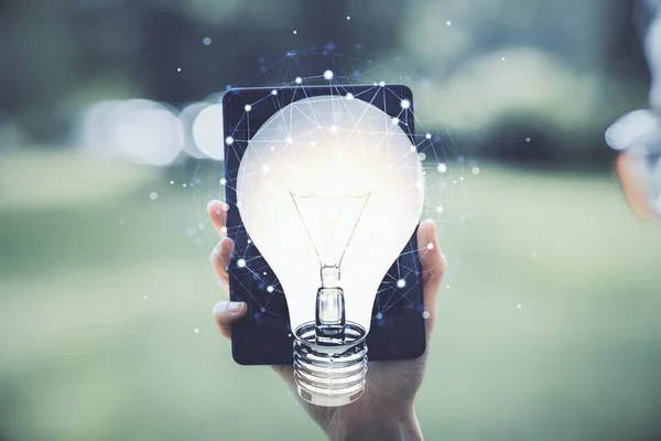 Double exposure of light bulb hologram and woman holding and using a mobile device. Idea concept.