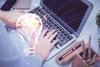 Bilgisayarda yazı yazan ve ampul çizen bir kadının ellerine iki kez maruz kalmış. Fikir kavramı.