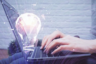 Bilgisayarda yazı yazan ve ampul çizen bir kadının ellerine iki kez maruz kalmış. Fikir kavramı.