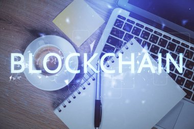 Masaüstü arkaplanındaki bilgisayarın üzerinden engelleme temalı hologram çizimleri. Üst Manzara. Çoklu maruz kalma. Kripto ekonomi kavramı.