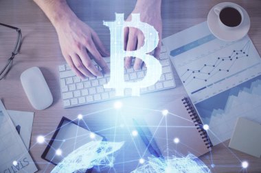 Bilgisayar klavyesinin ve şifreli para birimi temalı hologram çiziminin üzerine iki kez yazılan el pozu. Üst Manzara. Engelleme zinciri kavramı.