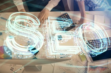 SEO hologram çizimleri ve birlikte çalışan kadın ve erkeğin çifte pozu. Arama motoru konsepti. Bilgisayar arkaplanı. Üst Görünüm.
