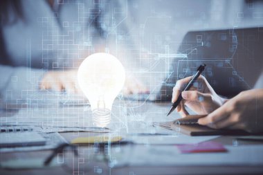 Bilgisayarda yazı yazan ve ampul çizen bir kadının ellerine iki kez maruz kalmış. Fikir kavramı.